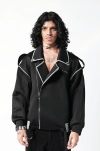 A person with curly hair wears a stylish black scuba jacket with silver accents and an open front